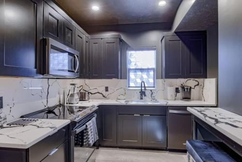 a kitchen with black cabinets and white counter tops at Elegant Black Modern in Lincoln