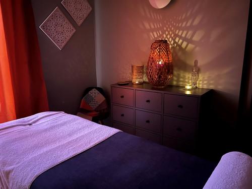a bedroom with a bed and a dresser with a lamp at The Originals Boutique, Hôtel de l'Univers, Montluçon in Montluçon
