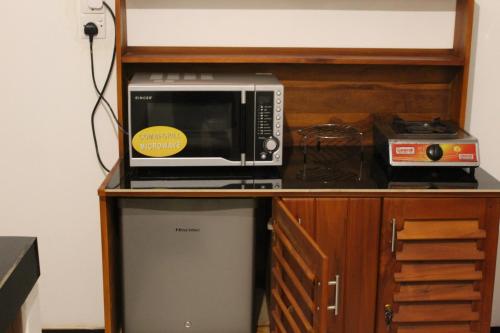 un microondas en la parte superior de una estantería de madera en Cottage 23, en Kurunegala