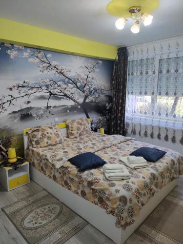 a bedroom with a bed with a tree mural on the wall at Family Rooms Hunedoara in Hunedoara