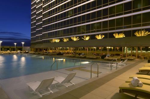Trump International Hotel Las Vegas في لاس فيغاس: مسبح الفندق مع كراسي الصالة والمبنى
