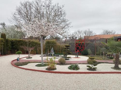 a garden with a park with a tree and a playground at une pause quelque part au jardin des érables et des niwakis in Saint-Médard-de-Guizières