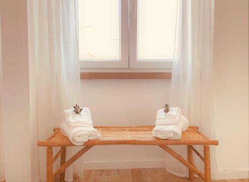 un banco de madera con toallas en una ventana en Cozy apartment with private courtyard en Barcarena