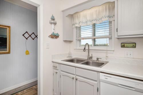a white kitchen with a sink and a window at A Dream Come True in Caswell Beach
