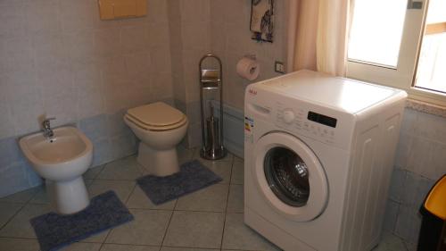 a bathroom with a washing machine and a toilet at Appartamento vista mare Poseidonia in Nebida