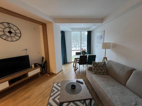 a living room with a couch and a clock on the wall at Apartman Blago Zlatibora in Zlatibor