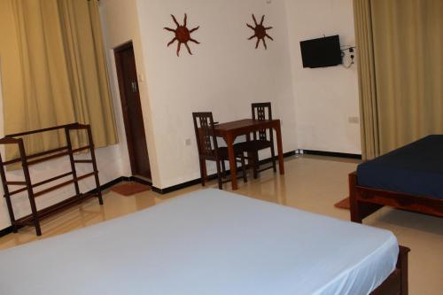 a bedroom with a bed and a table and chairs at Cottage 23 in Kurunegala