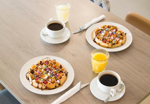 a table with two plates of waffles and two cups of coffee at Hampton By Hilton London City in London