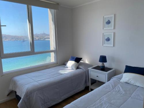 1 dormitorio con 2 camas y ventana grande en Departamento Playa Herradura Primera Línea, en Coquimbo