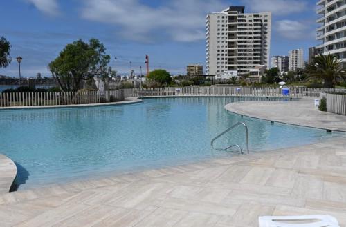 a large swimming pool with blue water in a city at Departamento Playa Herradura Primera Línea in Coquimbo