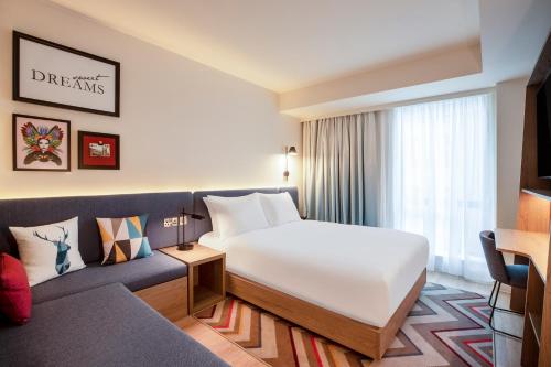 a hotel room with a bed and a couch at Hampton By Hilton London City in London