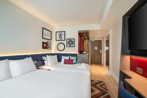a hotel room with a bed and a flat screen tv at Hampton By Hilton London City in London