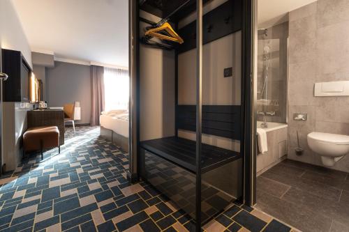 ein Bad mit einer Dusche und einem WC in der Unterkunft GINN Hotel Berlin Potsdam in Teltow