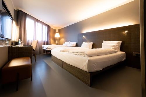 a hotel room with two beds and a desk at GINN Hotel Berlin Potsdam in Teltow