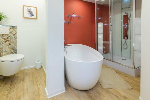 a white bathroom with a tub and a shower at Das Maximilian - Feines Landhotel am Schliersee in Schliersee