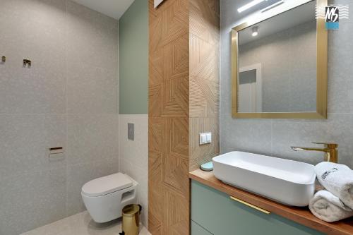 a bathroom with a sink and a toilet and a mirror at MS Apartments Rest 1.0 in Sopot