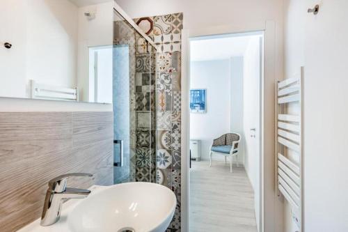 La salle de bains blanche est pourvue d'un lavabo et d'une douche. dans l'établissement Family & Friends Rooms, à Padoue