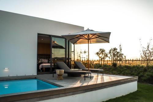 a patio with a swimming pool and an umbrella at Vergenoegd Löw Boutique Hotel & Spa in Cape Town