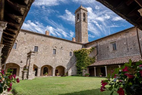 un grand bâtiment en pierre avec une tour d'horloge dans l'établissement Convento San Bartolomeo, à Abbadia San Salvatore