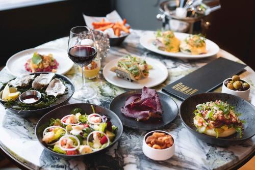 una tavola con piatti di cibo e un bicchiere di vino di Hotel Continental a Oslo