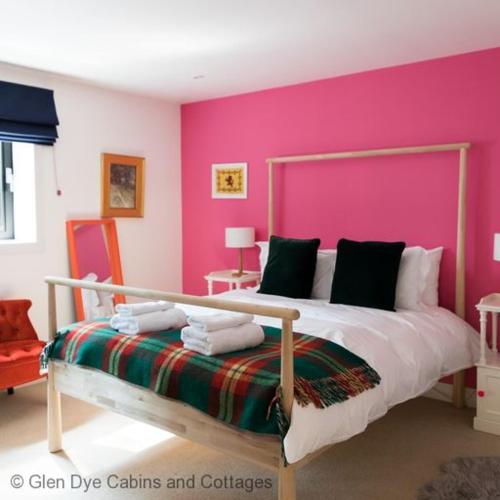 a bedroom with a large bed with a pink wall at Number 4 Steading Cottage in Banchory