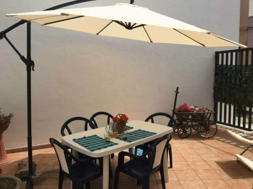 einen weißen Tisch mit Stühlen und einem Sonnenschirm in der Unterkunft Il tuo nido in Salento in Presicce