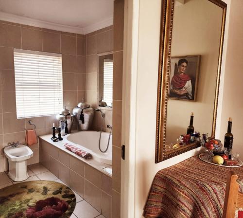 a bathroom with a tub and a toilet and a sink at Gordon's Beach Lodge in Gordonʼs Bay