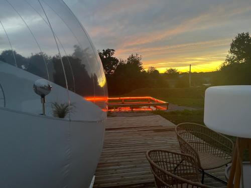 a boat sitting on a deck with a sunset in the background at Bubble Jade in Val Couesnon