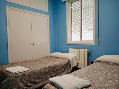 Villadesuso的住宿－Alojamiento Camino Portugues Oia，蓝色的客房设有两张床和窗户。