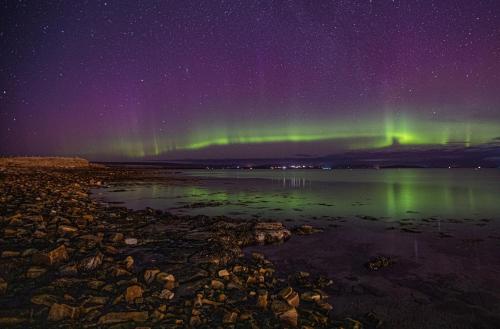 an aurora in the sky over a body of water at Stay Kirkwall Apartments - Ayre Road in Kirkwall