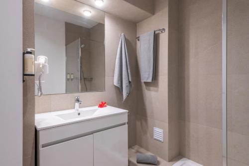 ein Badezimmer mit einem weißen Waschbecken und einer Dusche in der Unterkunft Emeralds Albufeira in Albufeira