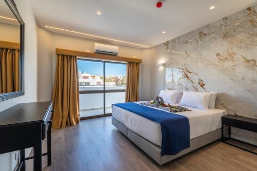 a hotel room with a bed and a desk and a window at Emeralds Albufeira in Albufeira