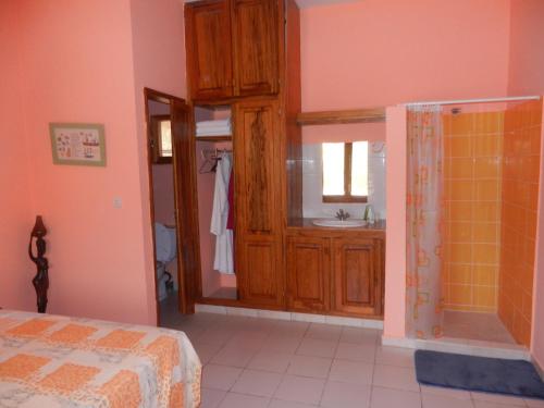 ein Schlafzimmer mit einem Bett und ein Badezimmer mit einem Waschbecken in der Unterkunft Villa au Tamtam in Gandigal