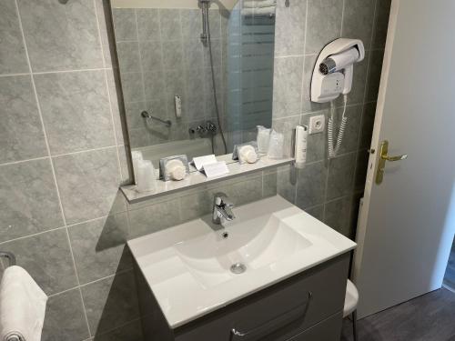 W łazience znajduje się biała umywalka i prysznic. w obiekcie Appartement Coeur de Ville w mieście Chinon