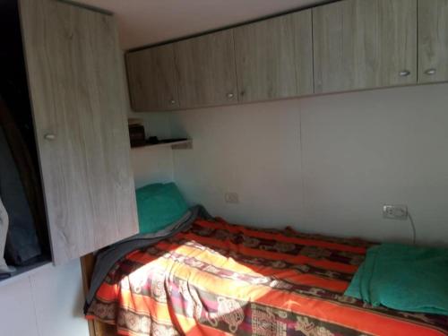a small bedroom with a bed with green sheets and cabinets at CONTAINERS-CASA in Ushuaia