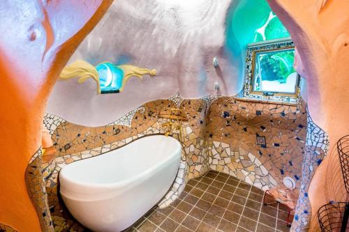 土と音の旅チオンの家 في أونا: حمام مع مرحاض في جدار من شجرة