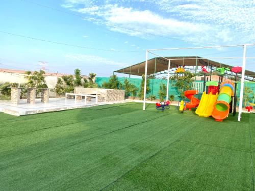 a large artificial lawn with slides and a playground at Luxury Farm with Swimming Pool and BBQ in Al Rahba