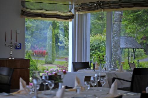 a dining room with white tables and chairs and a large window at Parkhotel Flora am Schluchsee in Schluchsee