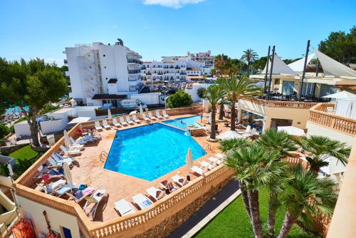 an overhead view of a swimming pool with chairs and palm trees at Apartamentos Azul Playa in Cala d´Or