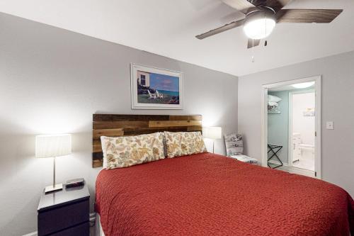 a bedroom with a red bed and a ceiling fan at Colony Club E1 in Gulf Shores