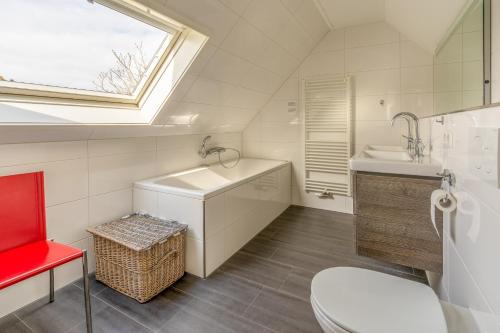 baño con lavabo y aseo y ventana en Villapark Kamperfoelie 77, en De Koog