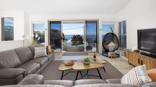 a living room with a couch and a tv at Dutchie's Sand & Sea Beach House - easy walk to the beach in Nelson Bay