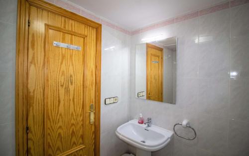 a bathroom with a sink and a wooden door at Las Terrazas - Apartamento en segunda línea Playa Cargador ALBERT VILLAS in Alcossebre