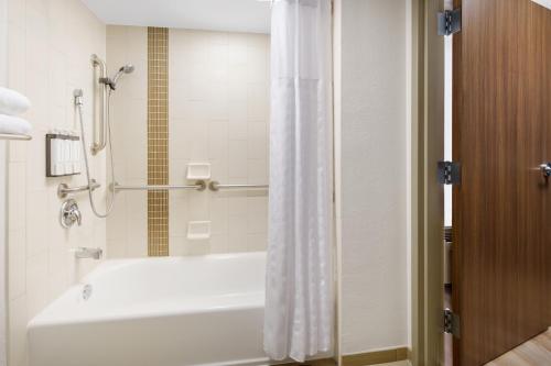 a bathroom with a tub and a shower with a shower curtain at Hyatt Place across from Universal Orlando Resort in Orlando