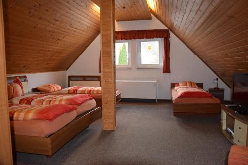 1 dormitorio en el ático con 2 camas y ventana en Ferienhaus Haus am Medebach, en Olsberg