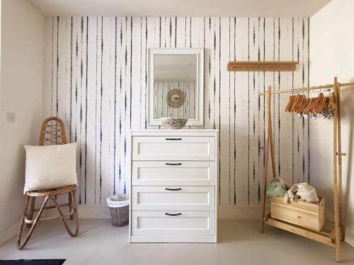 a white dresser with a mirror and a chair at Wild Sands Next to Beach ✩ Cinema ✩ Living Roof ✩ Games Room in Camber