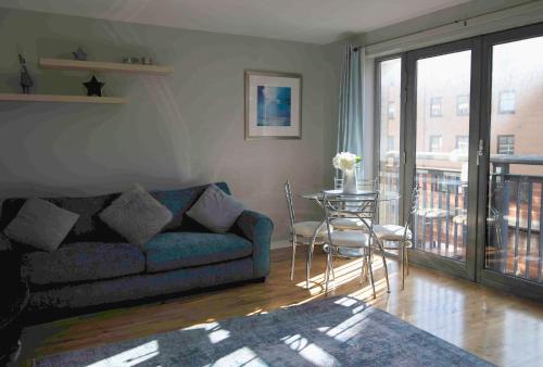 uma sala de estar com um sofá e uma mesa em Bright Contemporary Merchant City Flat in Central Location em Glasgow