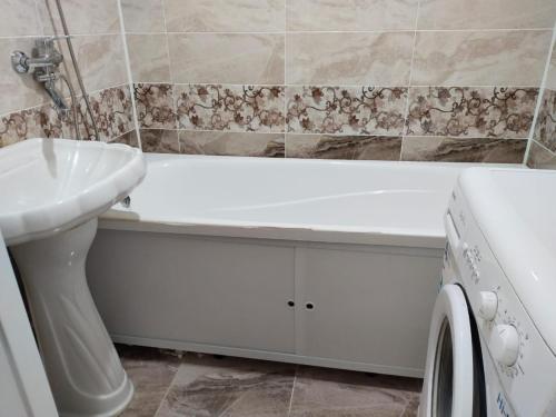 La salle de bains est pourvue d'une baignoire, d'un lavabo et d'un lave-linge. dans l'établissement Апартаменты в Хромтау. Энглер, à Khromtaū