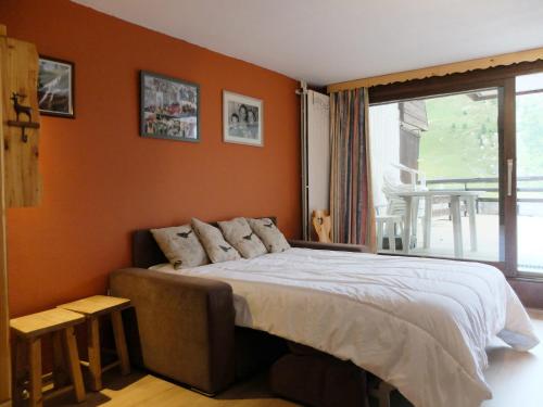 une chambre avec un lit avec un mur orange dans l'établissement Studio confort, balcon sud, au pied des pistes et commerces, animaux acceptés, Tignes Le Lac - FR-1-502-458, à Tignes