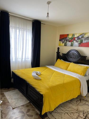 Un dormitorio con una cama amarilla con un animal de peluche. en Inviting 3-Bed Apartment in Nairobi en Nairobi